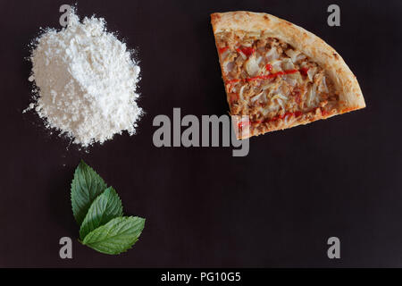 Tranche de thon au four pizza, tas de farine et de feuilles vertes sur fond noir Banque D'Images