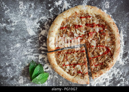 Pizza au thon et de feuilles vertes sur fond sombre parsemée de farine blanche Banque D'Images Pizza au thon et de feuilles vertes sur fond sombre parsemée de farine blanche Banque D'Images