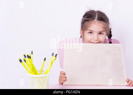 Mignonne petite fille dans l'uniforme scolaire est titulaire d'un tableau blanc vierge.focus sélectif et copie espace d'édition Banque D'Images