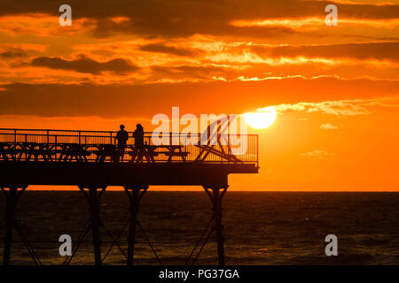 Pays de Galles Aberystwyth UK, jeudi 23 août 2018 UK Weather : un magnifique coucher de soleil sur les gens qui se profile sur la jetée de Aberystwyth, sur la côte ouest de la Baie de Cardigan au Pays de Galles, à la fin d'une journée de blustery cool vents violents et de fortes averses de pluie.La météo pour le week-end férié d'août devrait être très en suspens, avec de fortes pluies susceptibles pour de nombreux domaines Photo © Keith Morris / Alamy Live News Banque D'Images