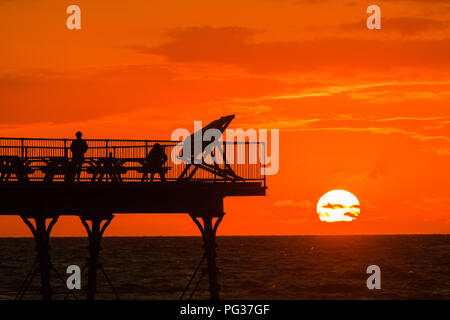 Pays de Galles Aberystwyth UK, jeudi 23 août 2018 UK Weather : un magnifique coucher de soleil sur les gens qui se profile sur la jetée de Aberystwyth, sur la côte ouest de la Baie de Cardigan au Pays de Galles, à la fin d'une journée de blustery cool vents violents et de fortes averses de pluie.La météo pour le week-end férié d'août devrait être très en suspens, avec de fortes pluies susceptibles pour de nombreux domaines Photo © Keith Morris / Alamy Live News Banque D'Images