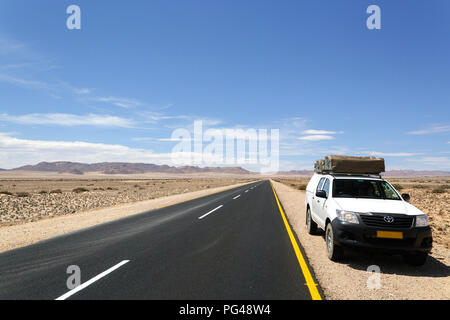 Location de 4x4 garé par une route asphaltée en paysage stérile en Namibie Banque D'Images