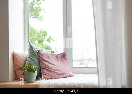 Oreillers carrés, plaid et des plantes à la fenêtre. Coin lecture Banque D'Images