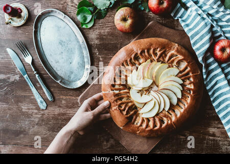 Vue partielle de la femme prenant morceau de tarte aux pommes maison sur planche à découper en bois Banque D'Images