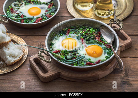 Shakshuka vert. Oeufs au plat avec des épinards frais, ramson, le poireau dans une casserole sur un fond gris, vue du dessus Banque D'Images
