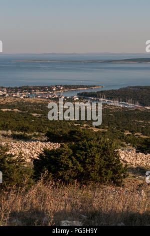 Croatie : vue panoramique au coucher du soleil de maquis méditerranéen et du port de Gajac, un petit village sur l'île de Pag, dans la mer Adriatique Banque D'Images