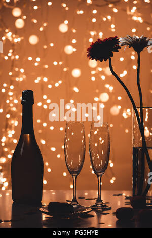 Vue rapprochée de bouteille de champagne, verres vides et bouquet de fleurs sur la table d'examen Banque D'Images