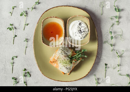 Vue de dessus de samossas en pâte filo farci aux épinards et de paneer décoré de graines germées de luzerne et de tournesol servi sur la plaque sur gris s Banque D'Images