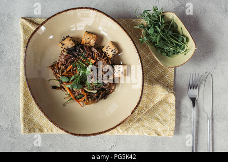 Composition des aliments aux germes dans un bol, avec le tofu et légumes soba décoré de graines germées de tournesol sur table gris Banque D'Images