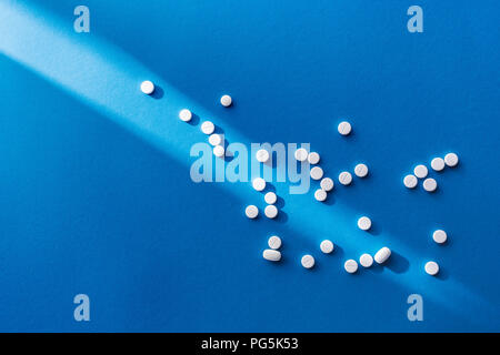 Vue de dessus de pilules blanches sur fond bleu avec du soleil Banque D'Images