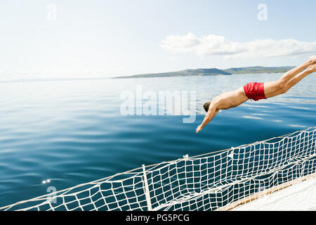 Jeune homme de sauter dans l'eau bateau Banque D'Images