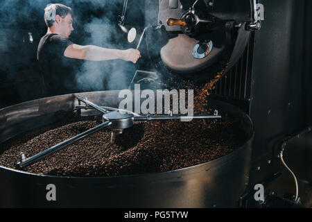 Professionnel hommes torrefacteur conteneur de grains de café avec machine à vapeur Banque D'Images