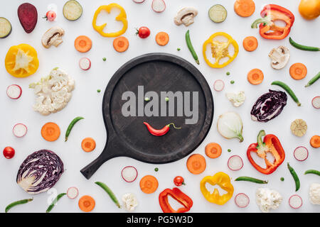 Vue de dessus du smiley face de pois verts et rouges sur planche de bois ronde isolated on white Banque D'Images