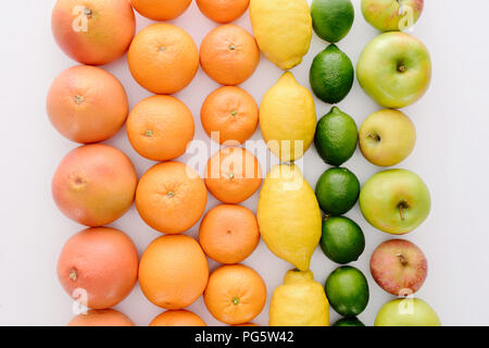 Vue de dessus de la composition de divers fruits mûrs en rangées sur la table blanche Banque D'Images