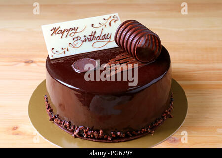 Mousse au chocolat Gâteau d'anniversaire recouvert de chocolat blanc carte de souhaits sur la table en bois Banque D'Images