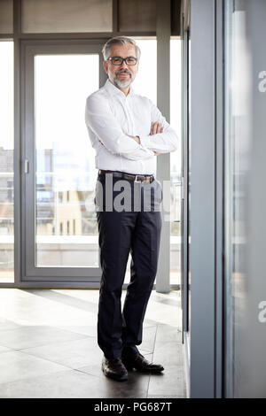 Portrait of smiling businessman standing à la fenêtre Banque D'Images