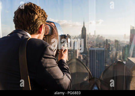 USA, New York City, l'homme regardant à travers des jumelles sur la plate-forme d'observation du Rockefeller Center Banque D'Images