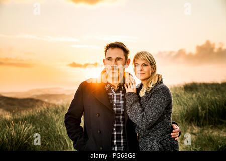 Couple standing in dunes au coucher du soleil Banque D'Images