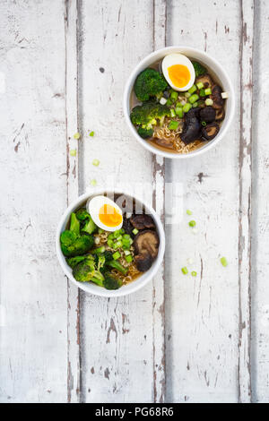 Deux bols de soupe de Ramen avec des œufs, du brocoli, des nouilles, des champignons shiitake et oignons de printemps Banque D'Images