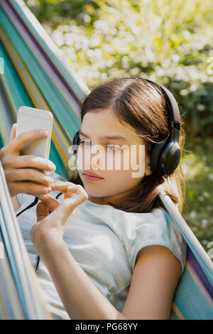 Portrait de jeune fille avec un casque et un téléphone intelligent en hamac Banque D'Images