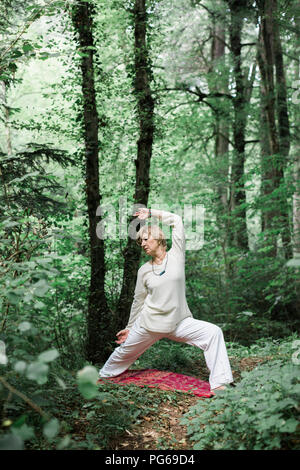 Senior woman doing yoga dans la forêt Banque D'Images