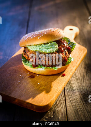 Burger au guacamole sur planche de bois Banque D'Images