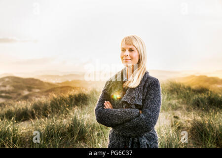 Smiling woman standing in dunes Banque D'Images