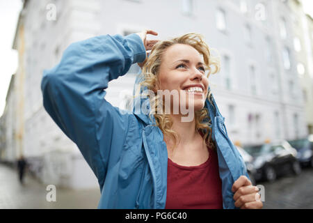 Portrait of smiling blonde woman putting sur sa capuche Banque D'Images