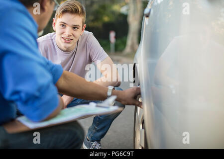 Pilote de l'apprenant avec moniteur Vérification du gonflage des pneus d'une voiture Banque D'Images