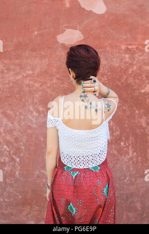 Vue arrière d'une jeune femme aux courts cheveux roux part de toucher l'extérieur du cou Banque D'Images