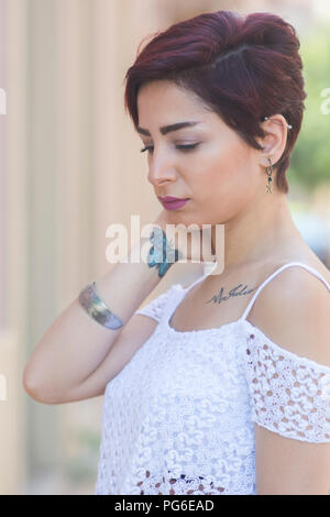 Belle jeune femme avec papillon tatouage au poignet cou toucher la main à l'extérieur Banque D'Images