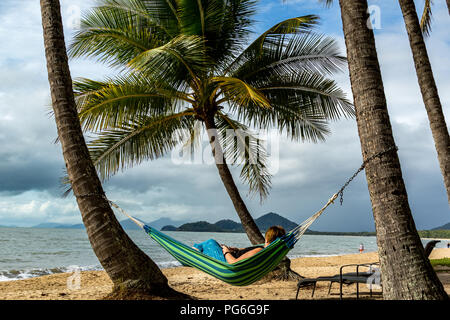 Woman laying in hammock donnant sur les palmiers et la plage Banque D'Images