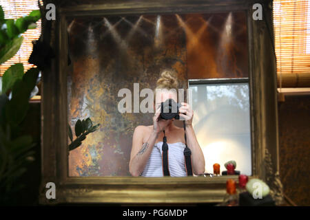 Image miroir de femme en tenant l'appareil photo dans la salle de bains avec selfies Banque D'Images