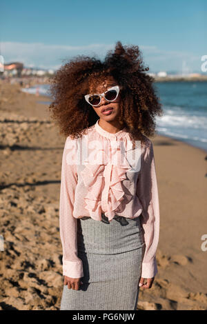 Portrait de la belle jeune femme à la coiffure afro debout sur la plage Banque D'Images