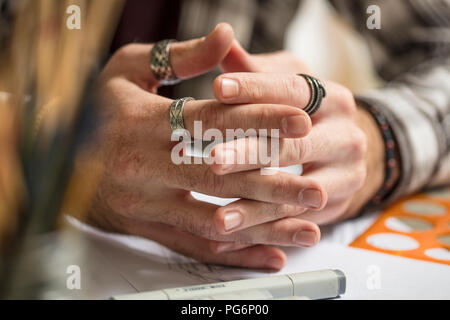 Close-up of artist's mains reposant sur la table Banque D'Images