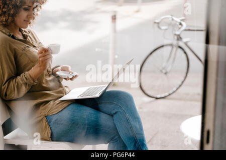 Femme travaillant dans un café, boire du café, using laptop Banque D'Images