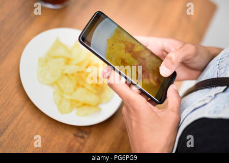 Woman's hands taking photo de chips with cell phone, close-up Banque D'Images