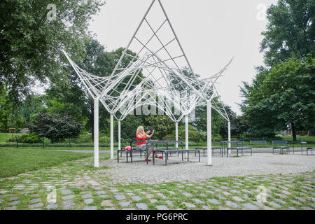 Femme enceinte, assise sur un banc de parc en tenant un avec une tablette selfies Banque D'Images