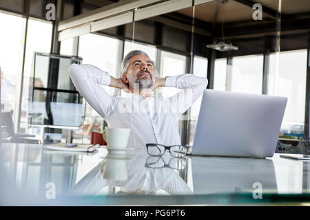 Businessman at desk in office penché en arrière Banque D'Images