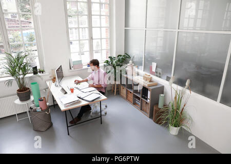 Man working at desk dans un bureau loft Banque D'Images