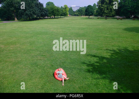 Femme assise au siège gonflable sur meadow looking at book Banque D'Images