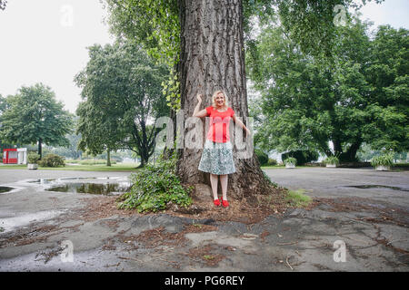 Portrait of smiling pregnant woman standing at a tree in park Banque D'Images