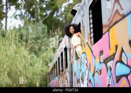 Fashionable young woman leaning out de fenêtre d'un vieux train détruit et abandonné Banque D'Images