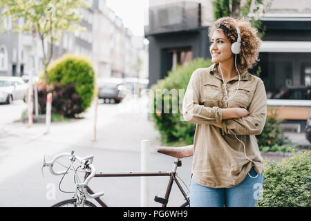 Femme dans la ville à l'écoute de la musique avec des écouteurs Banque D'Images