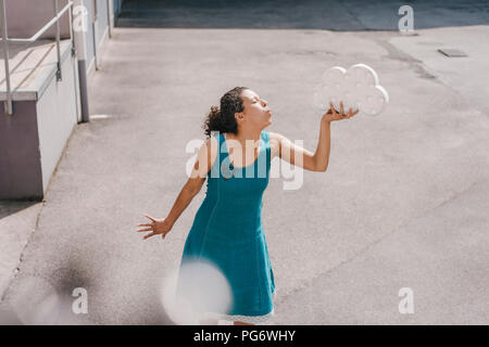 Femme debout dans la cour, holding, symbole nuage blowing kiss Banque D'Images