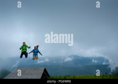 Allemagne, Brauneck, happy young couple randonneur avec des sacs de sauter en l'air Banque D'Images