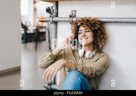 Jeune femme avec casque, travaillant en espace de coworking, parler au téléphone Banque D'Images