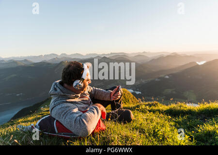 Randonneur couché dans l'herbe, faire une pause et d'écoute de la musique avec des écouteurs Banque D'Images