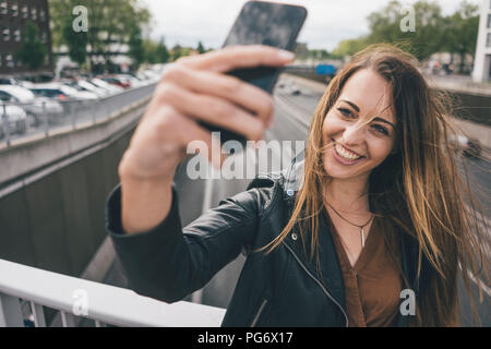 Jeune femme tenant un pont d'autoroute sur selfies Banque D'Images