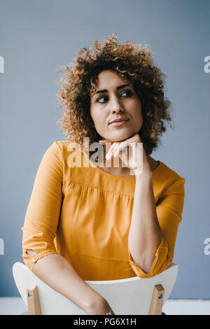 Femme assise sur une chaise, en pensant Banque D'Images